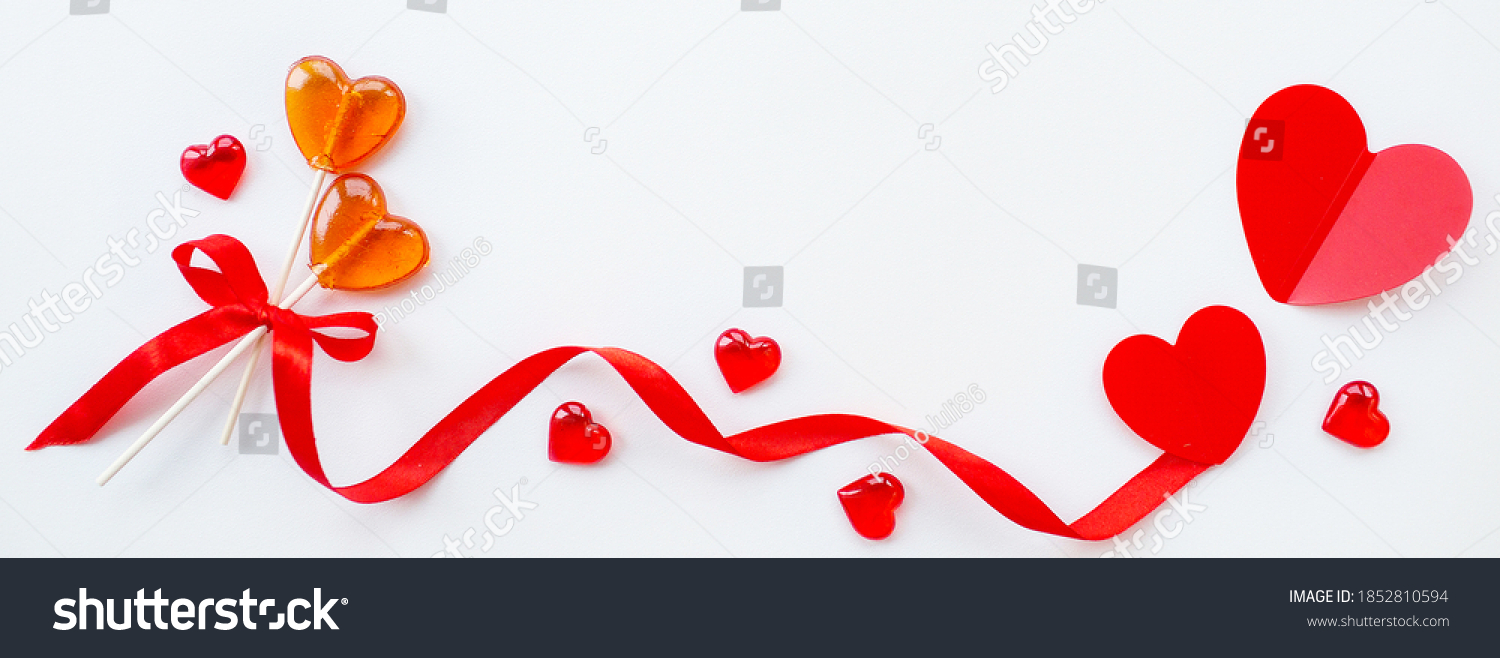 Banner.Two lollipops, red ribbon and hearts on a white background. Red hearts. Candy Love concept. Valentine's Day. Copy space for inscriptions. #1852810594