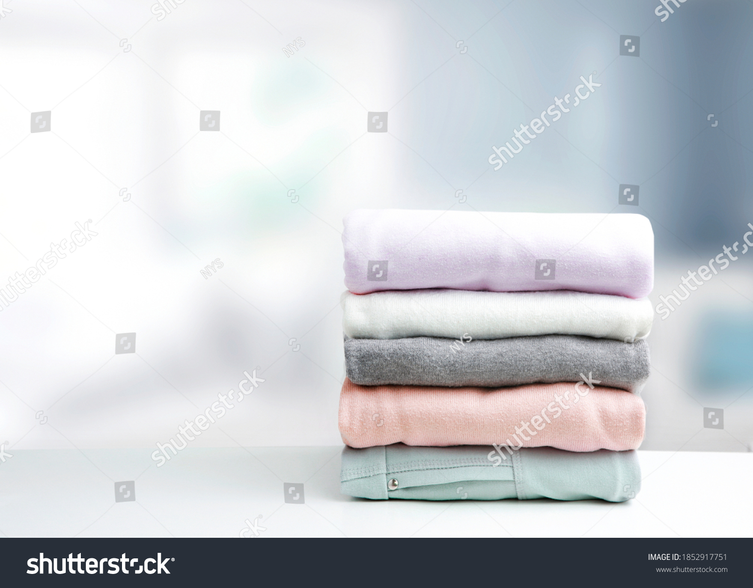Soft colors stack of clothing,clothes folded on table empty copy space background.Colorful garment stacked. #1852917751