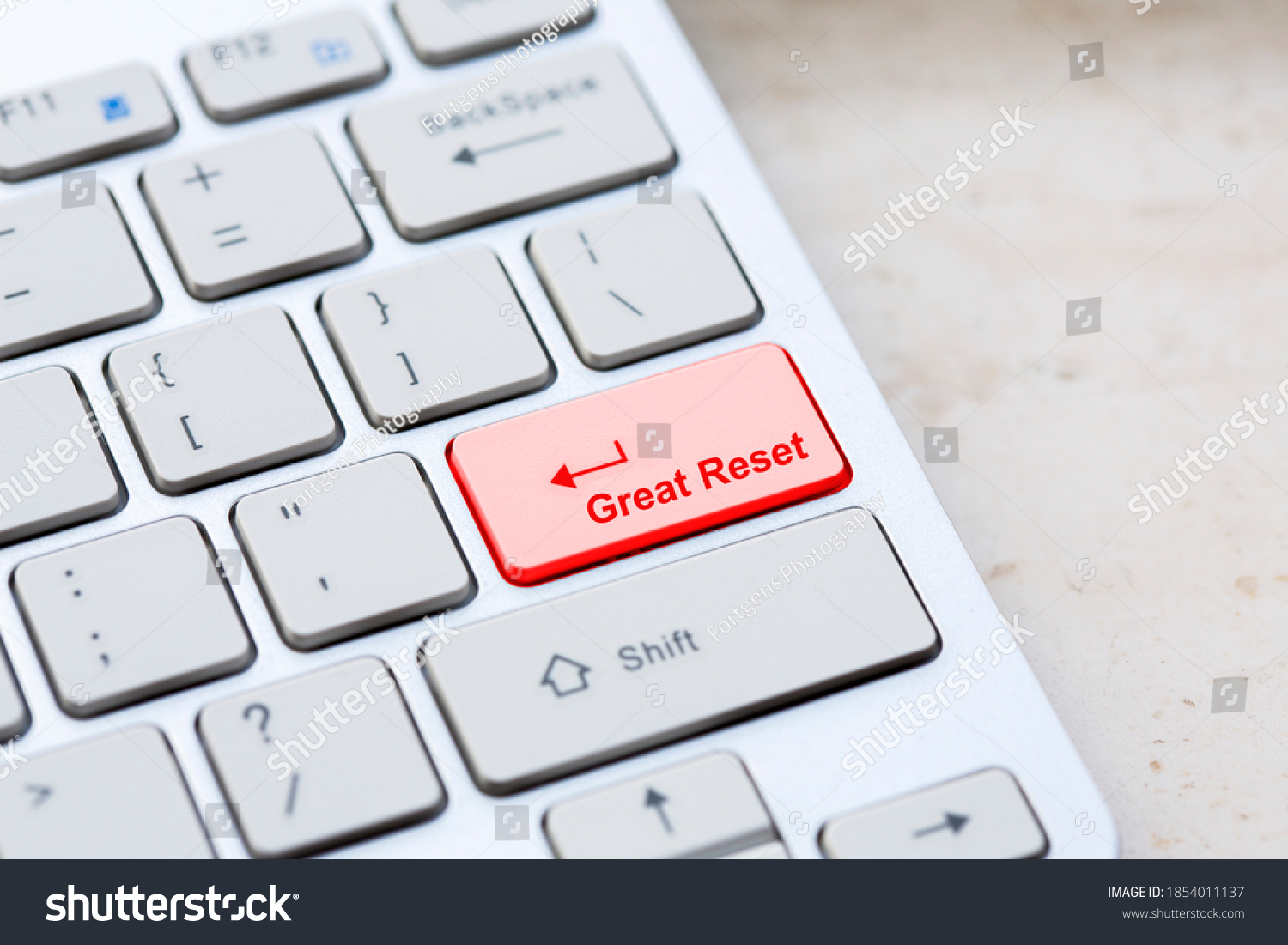 Silver grey keyboard close up with world global great reset enter- button on marble background. #1854011137