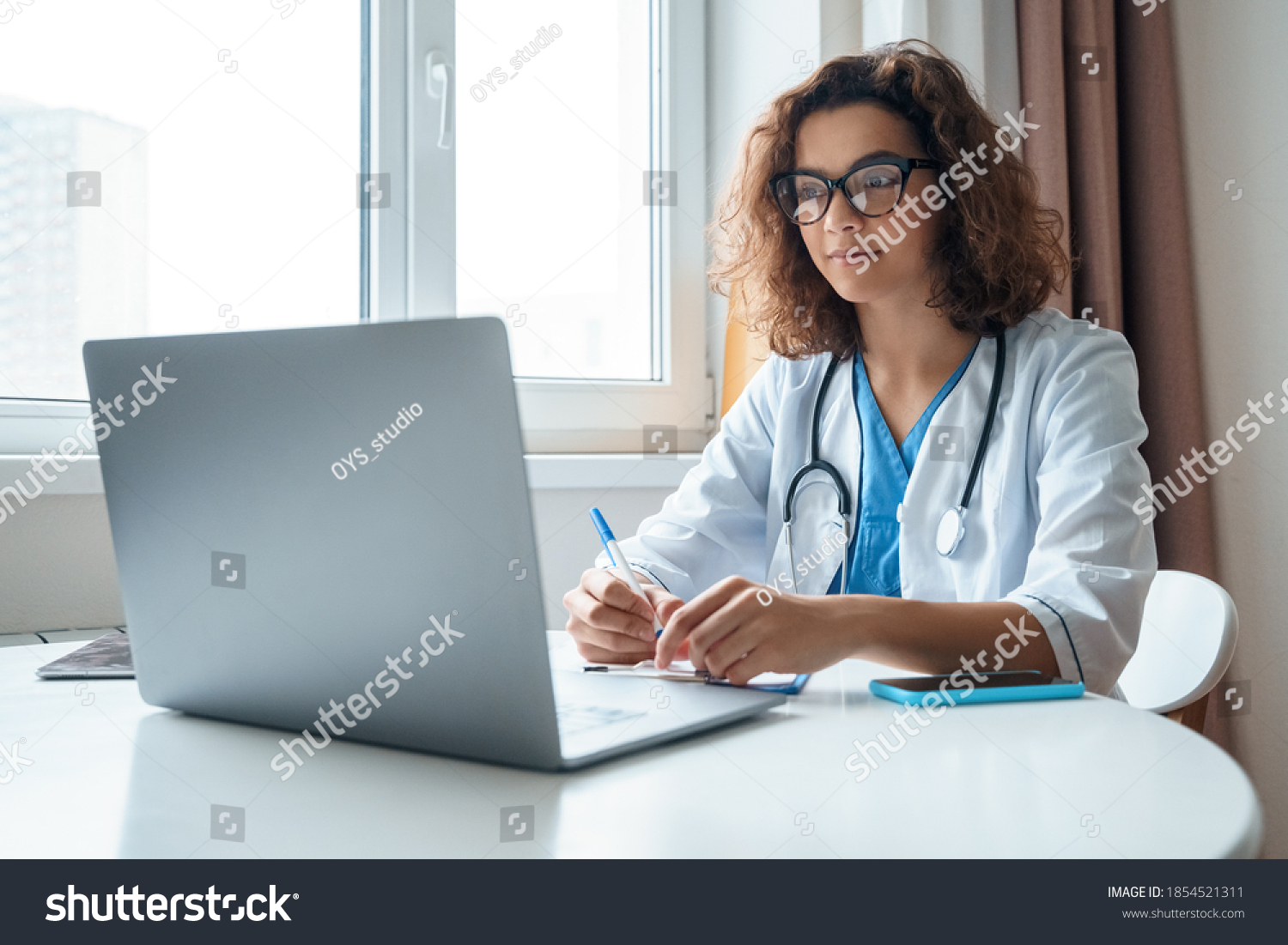 Attractive female doctor make online video call consult patient on laptop. Medical assistant young woman therapist videoconferencing to web camera. Telemedicine concept. Online doctor appointment. #1854521311