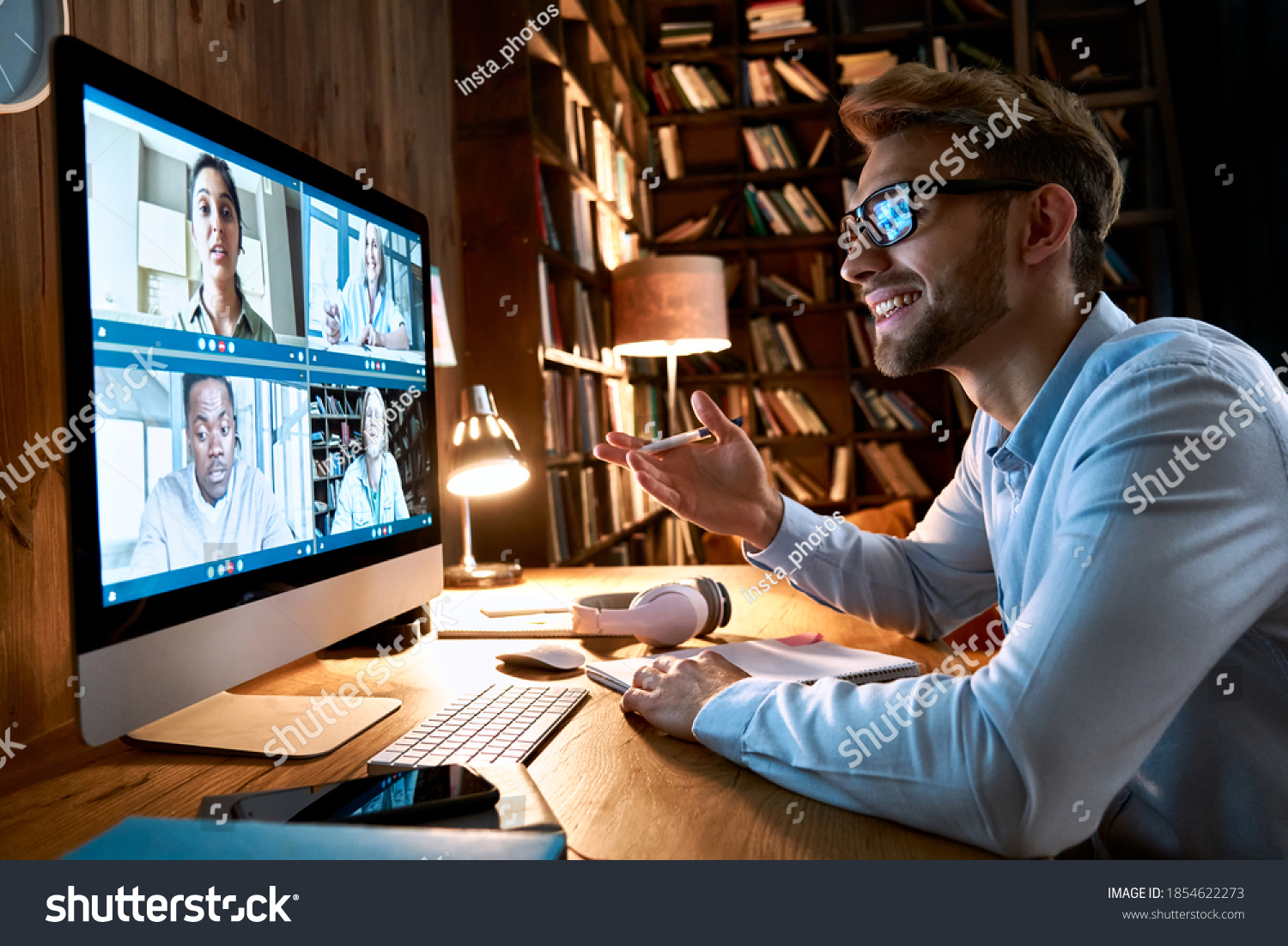 Business man having virtual team meeting on video conference call using computer. Social distance worker working from home office talking to diverse colleagues in remote videoconference online chat. #1854622273