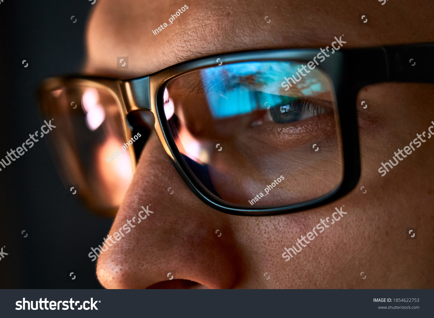 Close up view of focused businessman wears computer glasses for reducing eye strain blurred vision looking at pc screen with computer reflection using internet, reading, watching, working online late. #1854622753