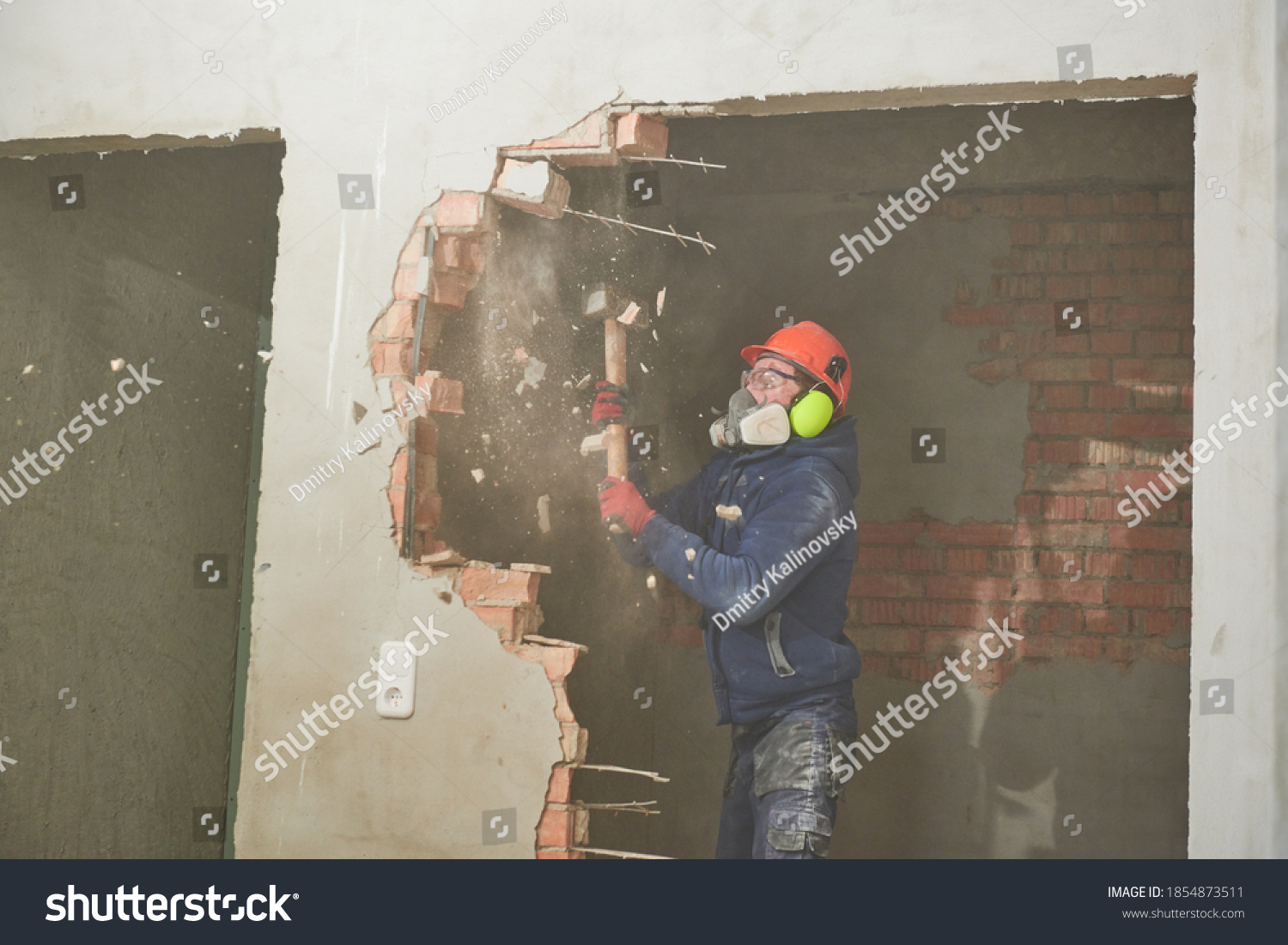 demolition work and rearrangement. worker with sledgehammer destroying wall #1854873511
