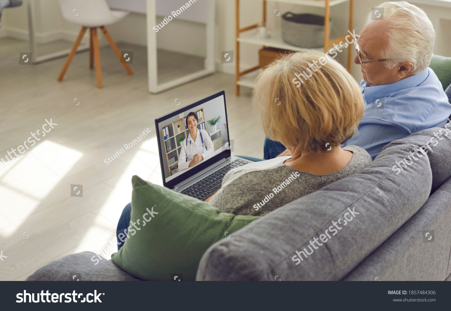 Using eHealth and telemedicine services at home. Couple of senior patients sitting on sofa with laptop, having video call with online doctor and getting professional health consultation #1857484306