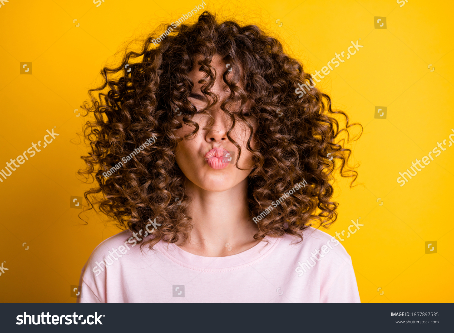 Headshot of girl with curly hairstyle wearing t-shirt send air kiss pouted lips isolated on vivid yellow color background #1857897535