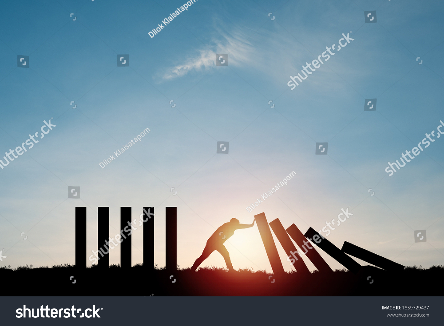 Silhouette man pushing rectangle  block which falling to stop dominos others rectangle standing with blue sky. Risk and crisis management concept. #1859729437