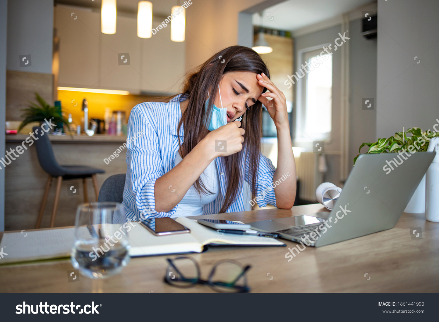 Woman working in the office and having difficulties breathing with face mask, she is pulling the mask down. The woman had to remove the mask to breathe after having to wear it for a long time #1861441990