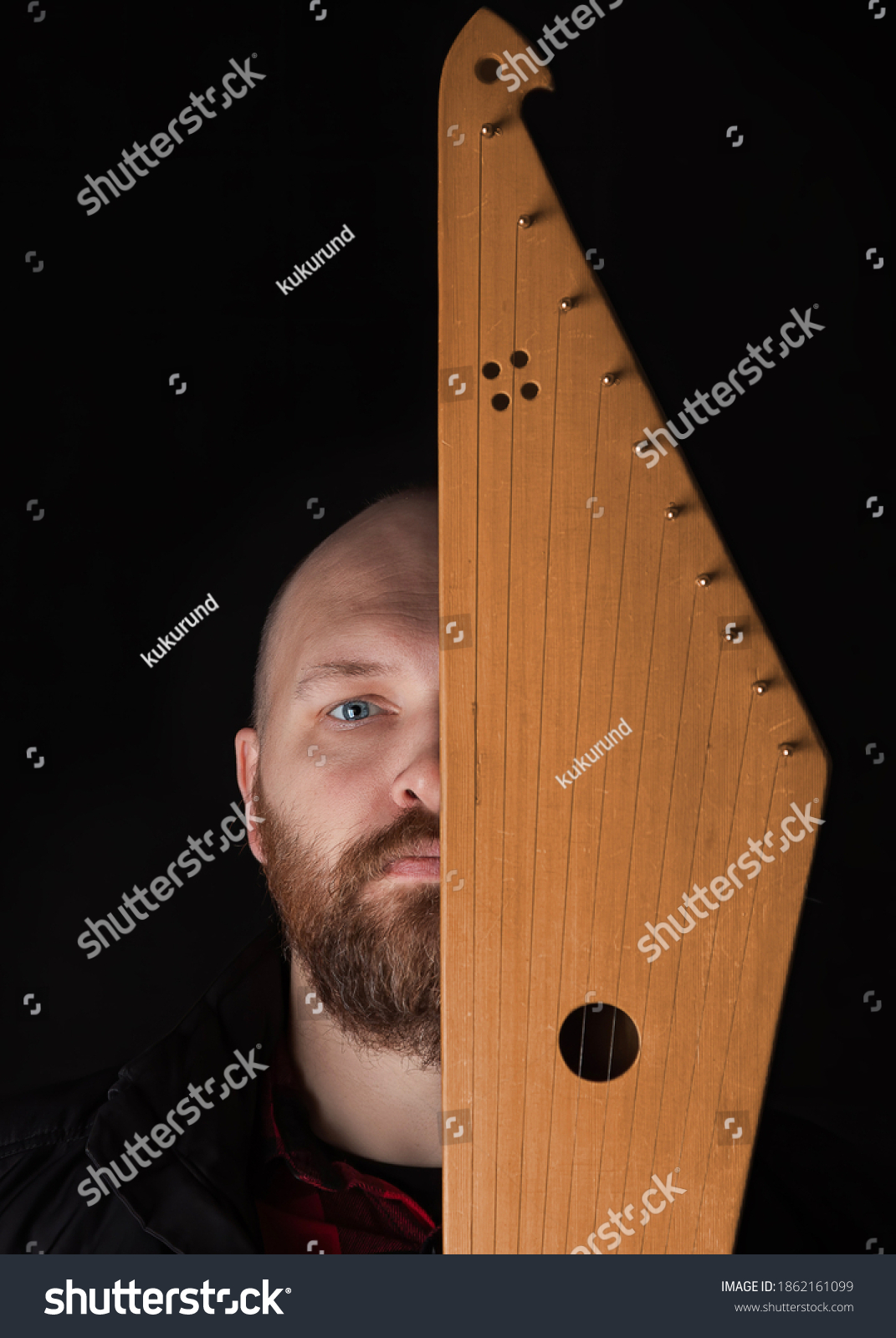 Bearded man hides his face behind Kantele, a national Finnish and Karelian musical instrument, also known as the psaltery (gusli) in Russia and as the kankles, kokle, and Kannel in the Baltic States. #1862161099