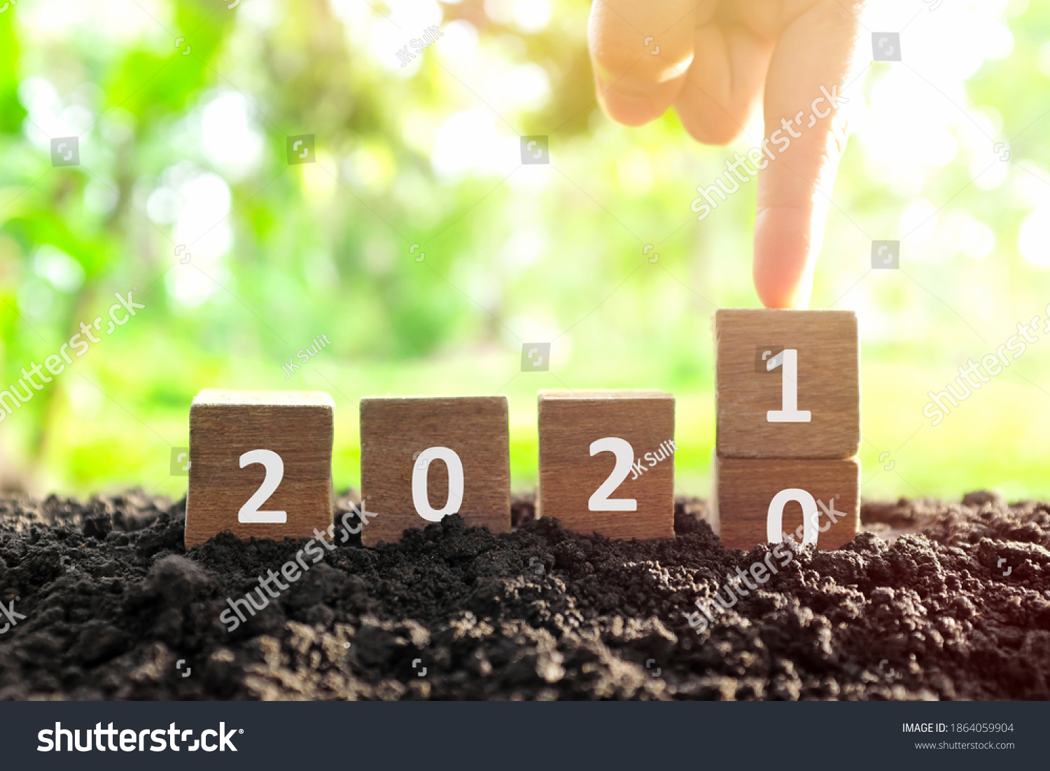Male hand bury year 2020 to change to 2021 in wooden blocks cubes. New year, hello and goodbye concept. #1864059904
