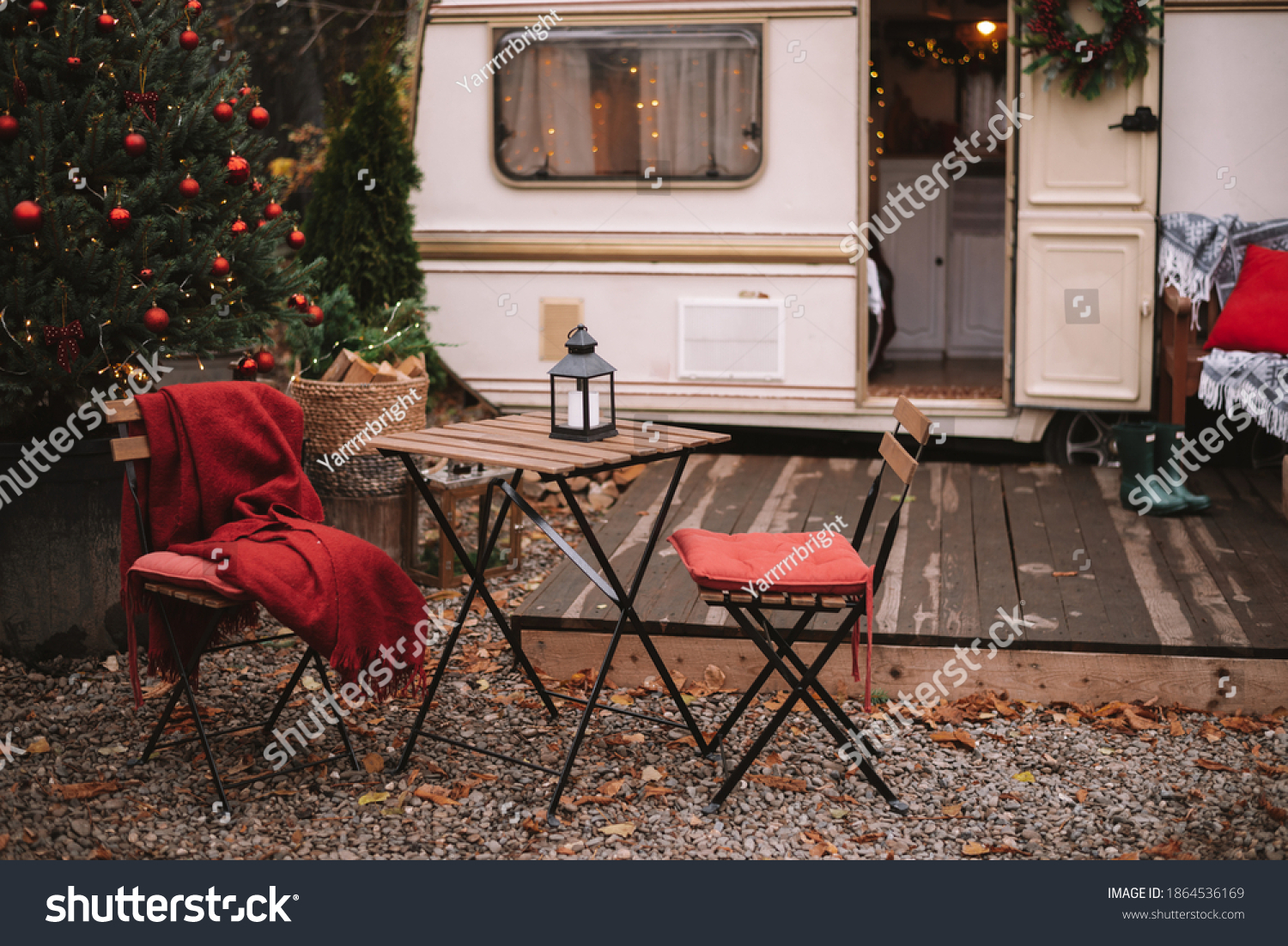 Caravan mobile home with terrace, Mobile home decorated with Christmas decor. Festive atmosphere - lights, red blankets, Christmas trees. Waiting for the snow. Caravan camping. mobile home trailer. #1864536169