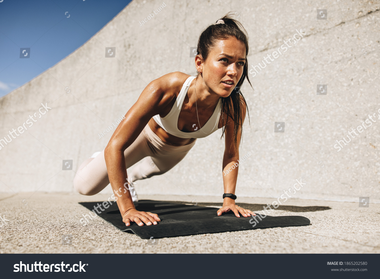 Fitness woman doing wide mountain climbers exercise. Female in sportswear exercising on fitness mat outdoors. #1865202580