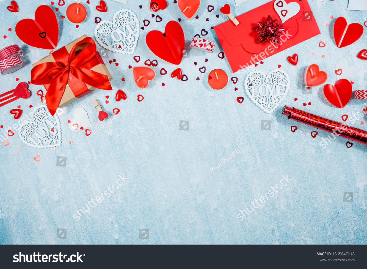 Greeting card for Valentine's Day. Red hearts, gift box, roses and candles on a blue background. Beautiful frame for text. Flatly. Copy the space. The concept of holiday and love. #1865647918