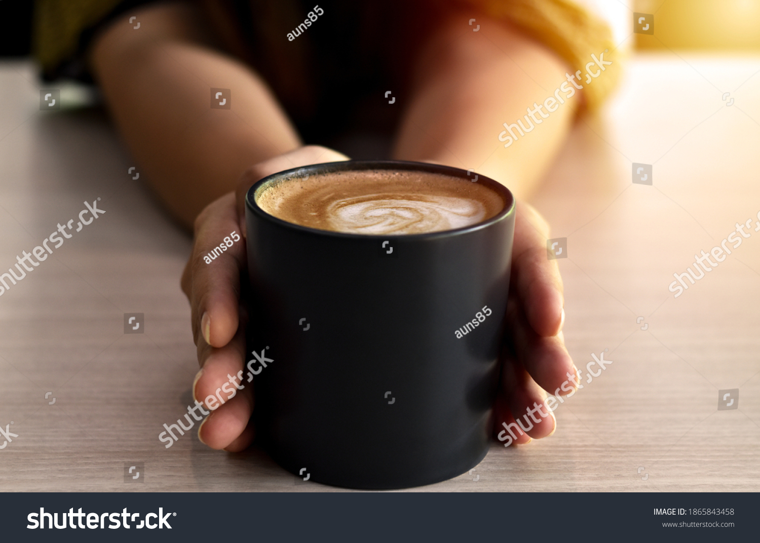 Warm coffee in a black mug with woman hand. #1865843458