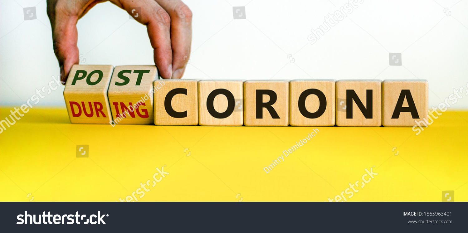 Symbol for a post-corona time. Male hand turns cubes and changes the words 'during corona' to 'post-corona'. Beautiful yellow table, white background. Medical and covid-19 post-pandemic concept. #1865963401