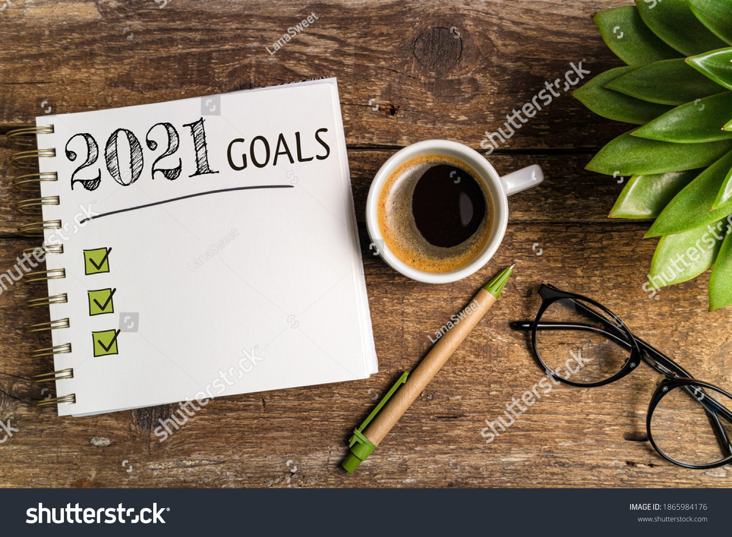 New year goals 2021 on desk. 2021 goals list with notebook, coffee cup, plant on wooden table. Resolutions, plan, goals, checklist, idea concept. New Year 2021 template, copy space
 #1865984176