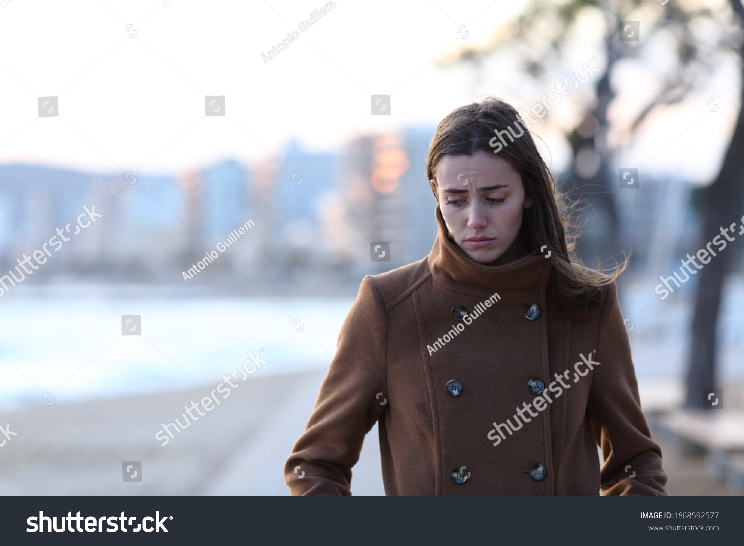 Front view portrait of a sad woman walking alone towards camera looking down on the beach in winter #1868592577