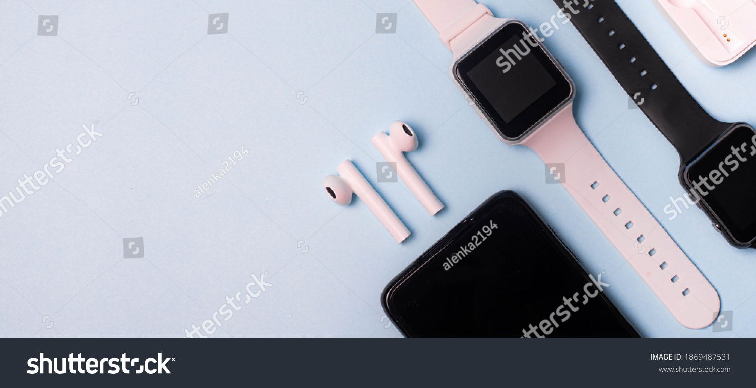 The layout of the watch and the phone on a blue background. Appliances and electronics. Modern gadgets. Phone headphones watch. Business. Wireless headphone. Watch with pedometer. #1869487531