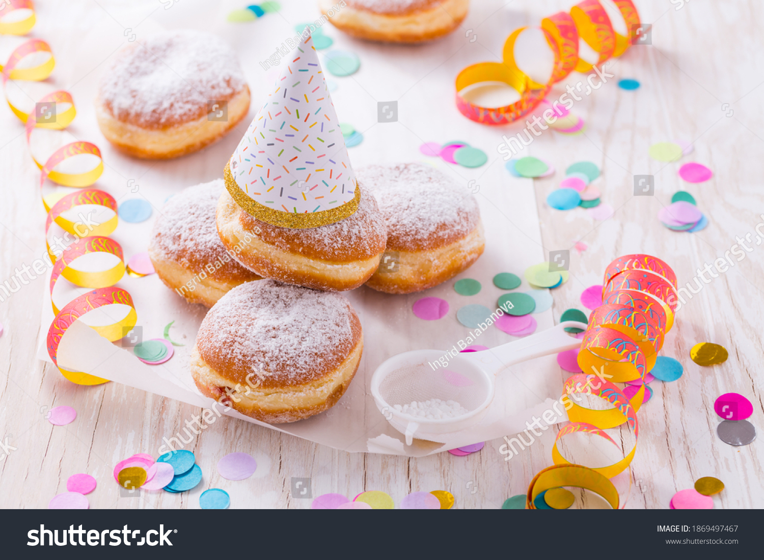 Traditional Berliner with party hat for carnival and party. German Krapfen or donuts with streamers and confetti. Colorful carnival or birthday image #1869497467