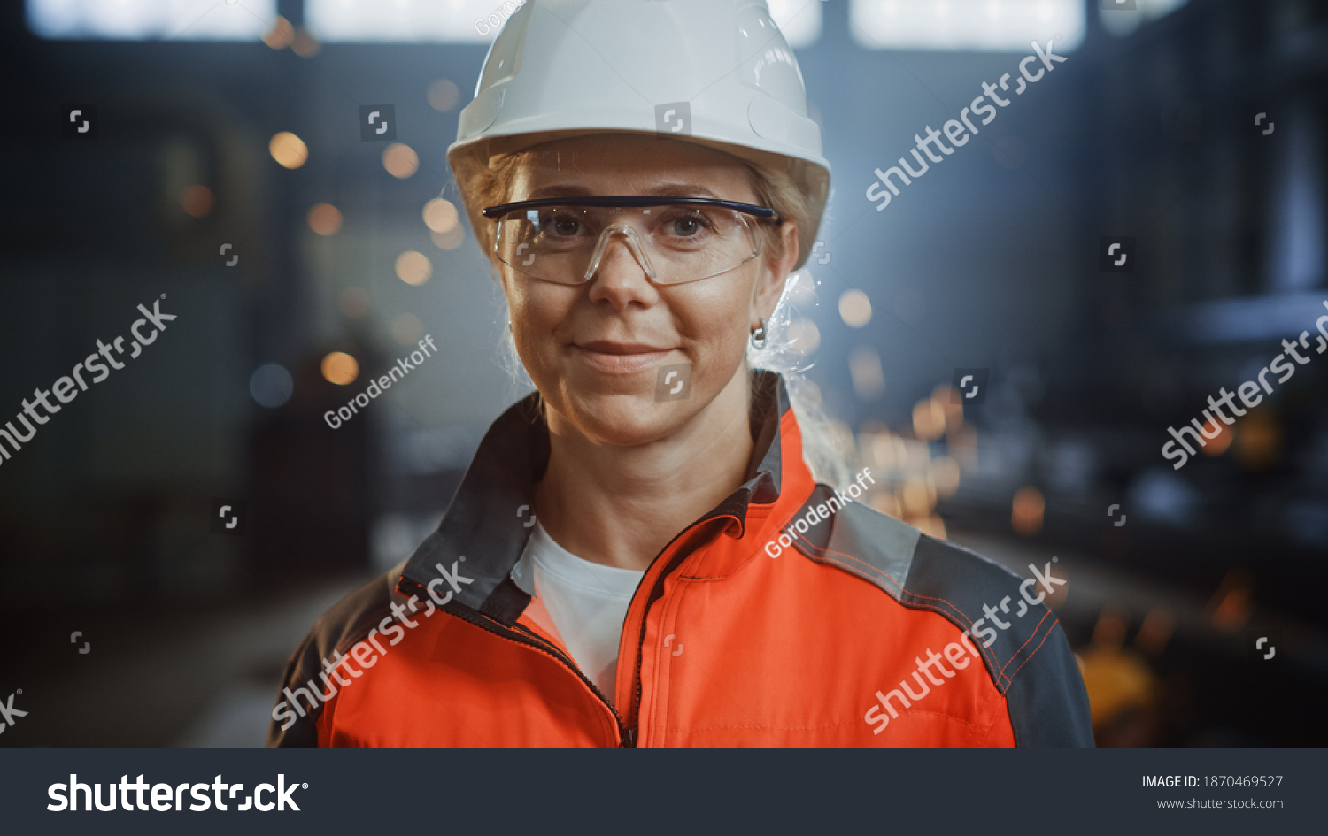 Portrait of a Professional Heavy Industry Engineer Worker Wearing Uniform, Glasses and Hard Hat in a Steel Factory. Beautiful Female Industrial Specialist Standing in Metal Construction Facility. #1870469527