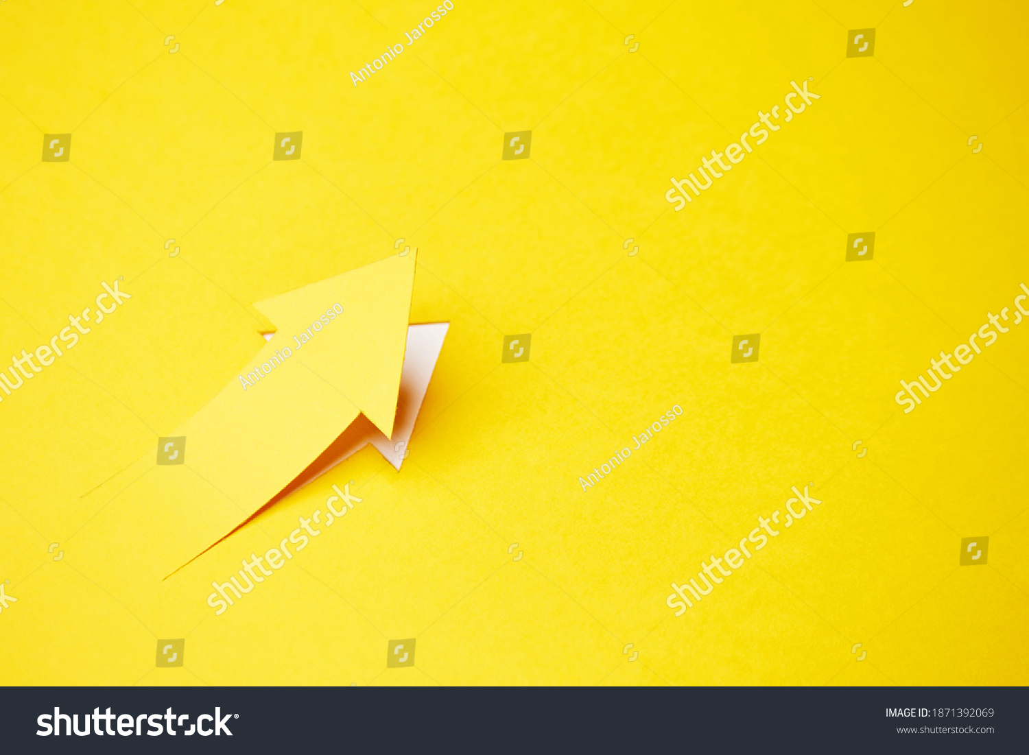 Right-up arrow cutted from solid sheet of yellow paper and curved up of one side with white paper underlay showing growth of stock market or up direction #1871392069