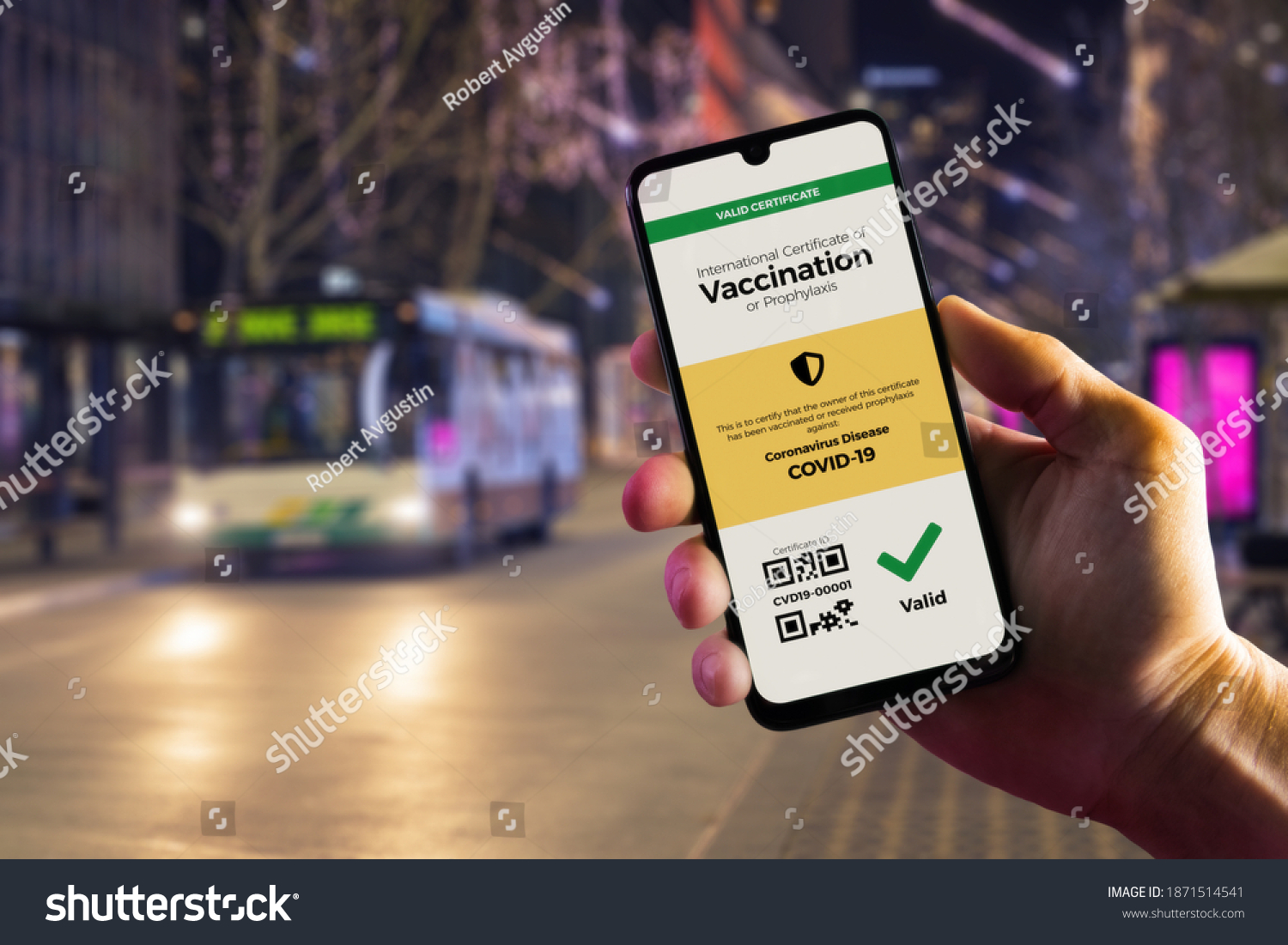 Smartphone displaying a valid digital vaccination certificate for COVID-19 in male's hand, downtown and city bus in background. Vaccination, disease immunity passport, health and surveillance concepts #1871514541