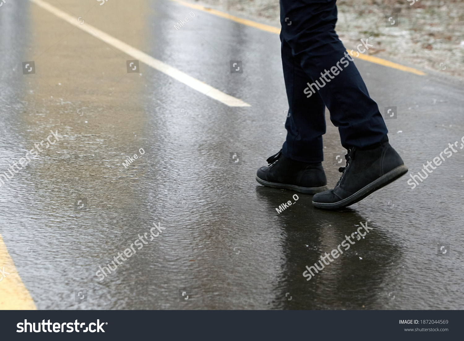 Ice crusted ground, a man walking on a slippery street, icy sidewalk, winter weater #1872044569