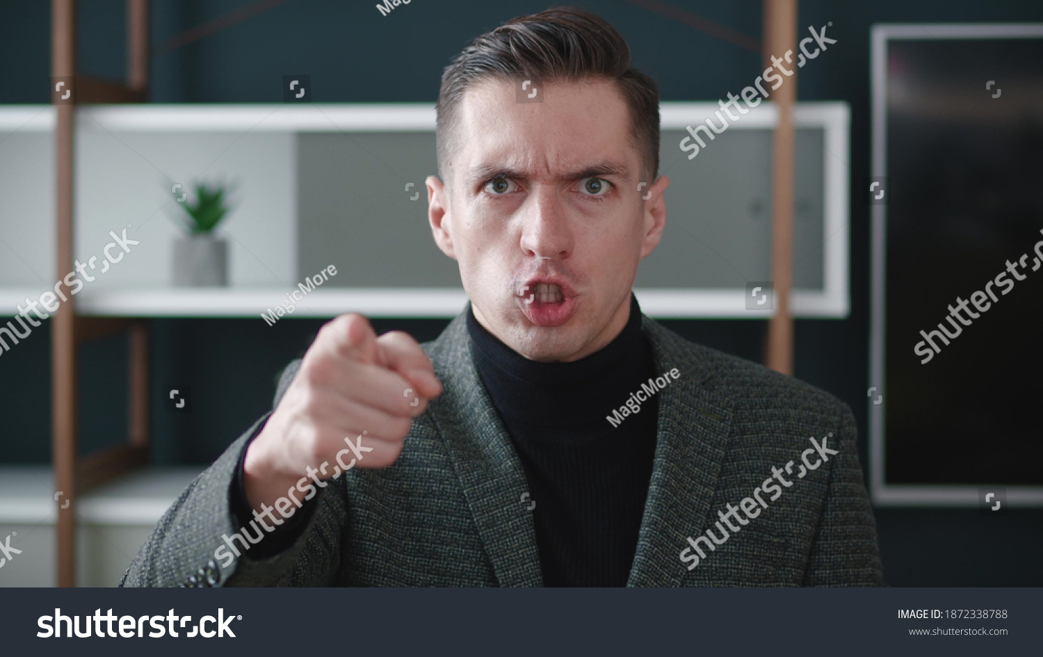 Close-up angry businessman shouting and pointing at camera. Portrait of aggresive boss scolding and shouting at employees threatening with a finger and shouting at the camera. #1872338788