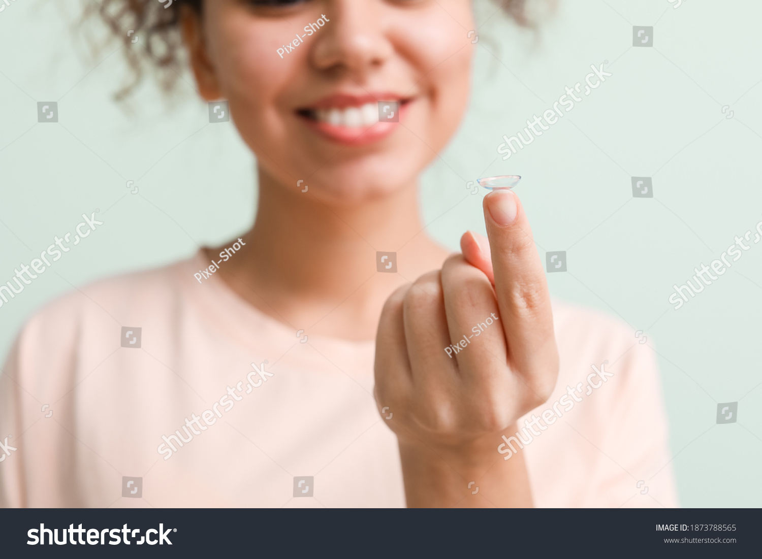 Young African-American woman with contact lens on color background #1873788565