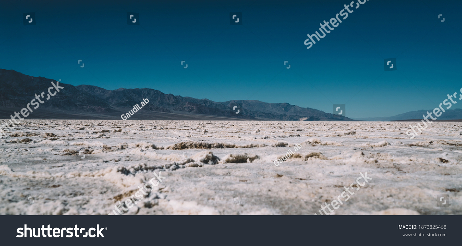 Ground level of picturesque desert with snowy rough surface located near cold hills covered with hoarfrost during sunny day of severe winter #1873825468