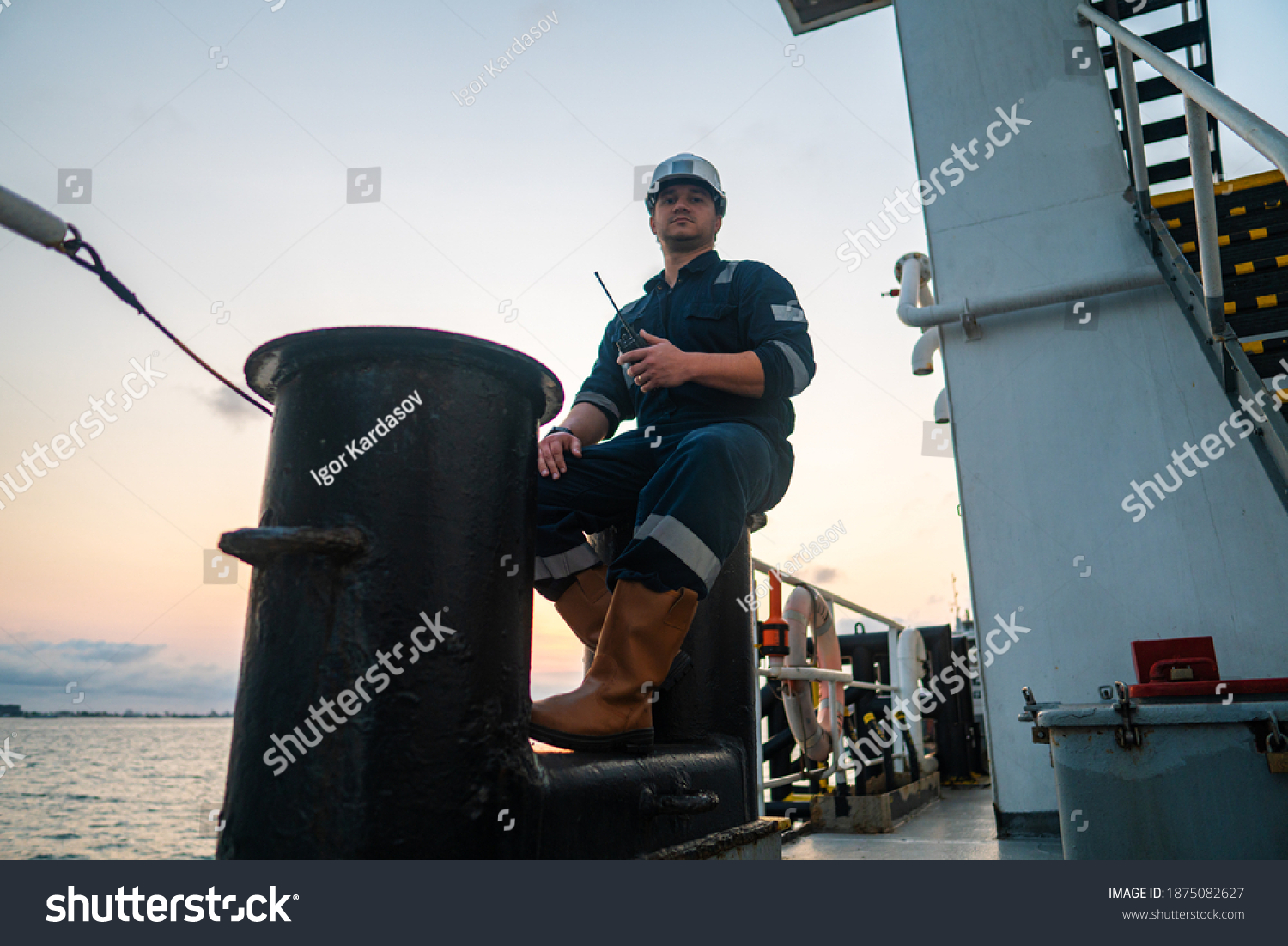 Marine Deck Officer or Chief mate on deck of offshore vessel or ship , wearing PPE personal protective equipment - helmet, coverall. Ship is on background #1875082627
