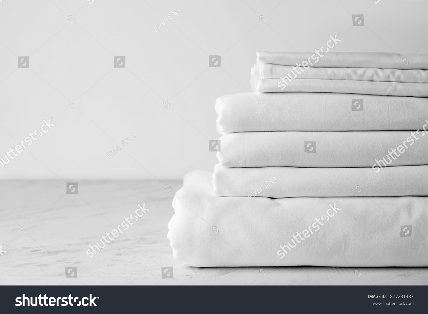 Stack of clean bed sheets on table #1877231437