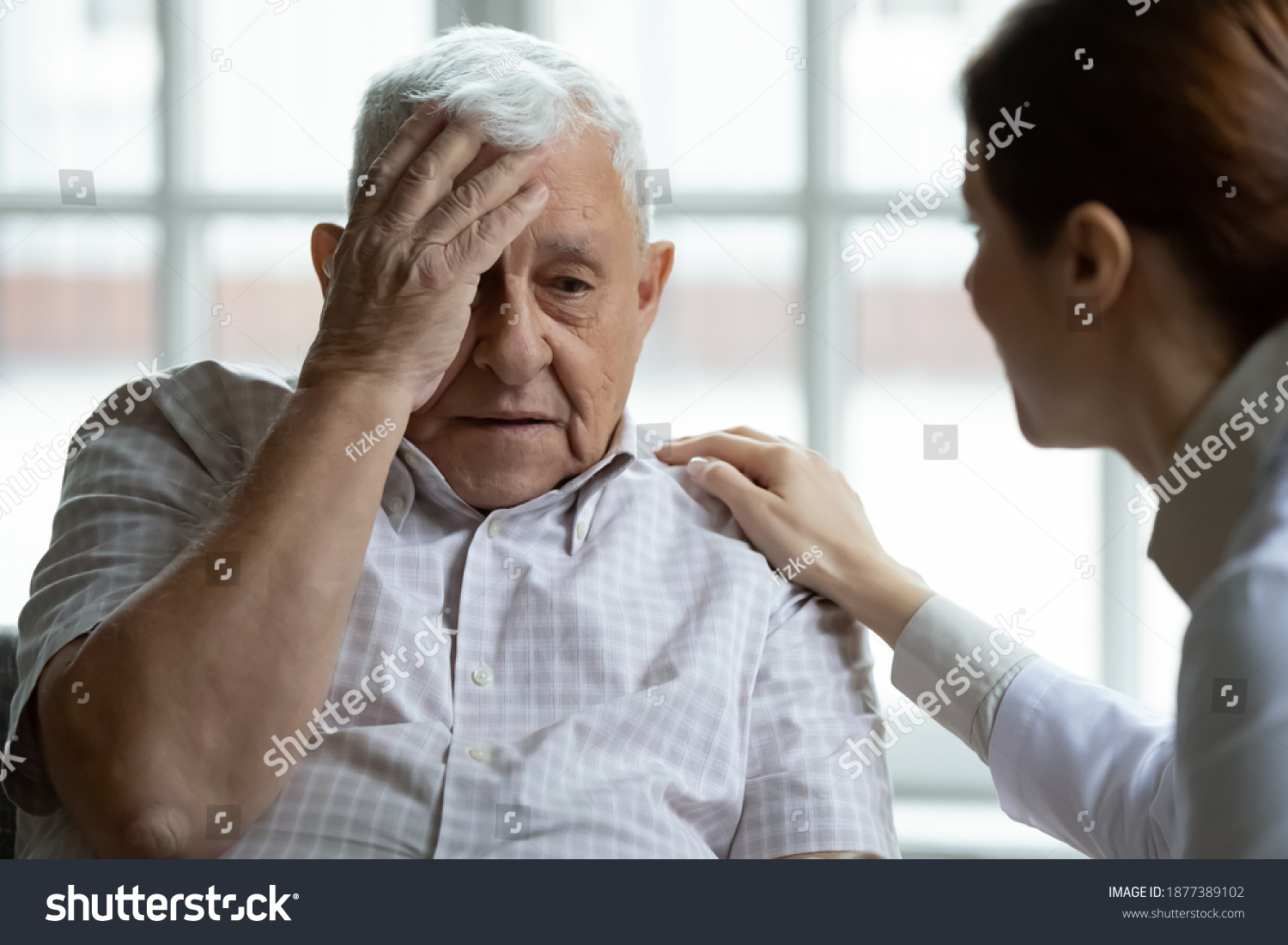 Attentive young lady physician interview senior patient on meeting listen to complaints make diagnosis. Stressed sad elderly man visit trusted capable doctor feel headache dizzy problems with memory #1877389102