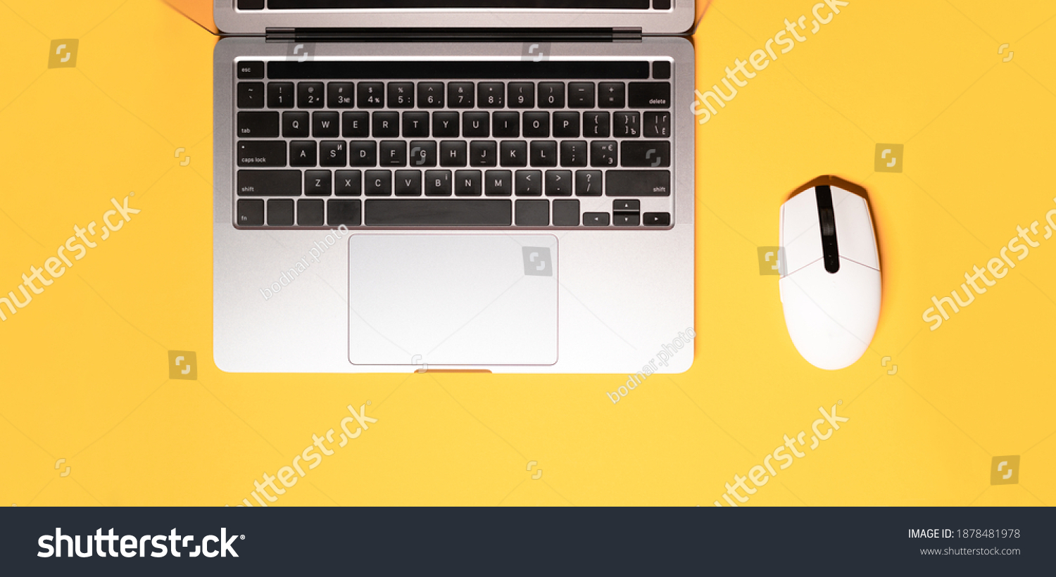 Horizontal flat lay minimalist photo with a silver grey laptop computer, and a wireless white-colored mouse on a yellow background. #1878481978