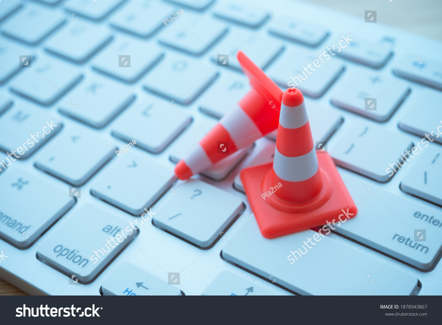 Maintenance, repair, under construction in computer system from virus or ransomware concept. Close up orange white traffic warning cones or pylon on keyboard computer background with copy space. #1878943867