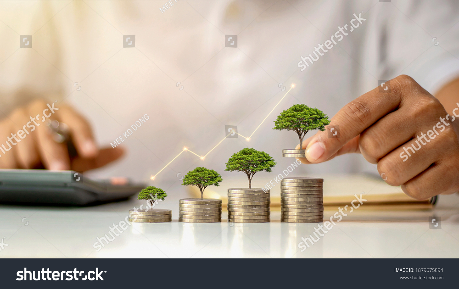 A businessman holding a coin with a tree that grows and a tree that grows on a pile of money. The idea of maximizing the profit from the business investment. #1879675894