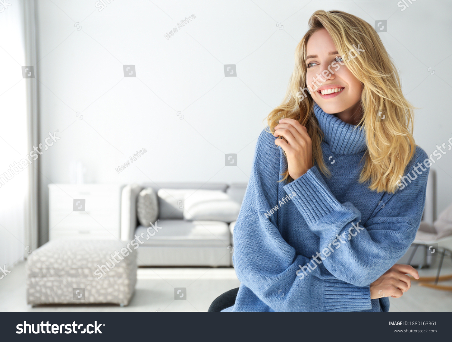 Beautiful young woman wearing warm blue sweater at home. Space for text #1880163361