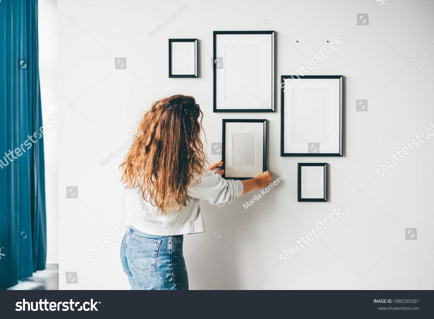 Woman hanging a frame on a wall. #1880285581