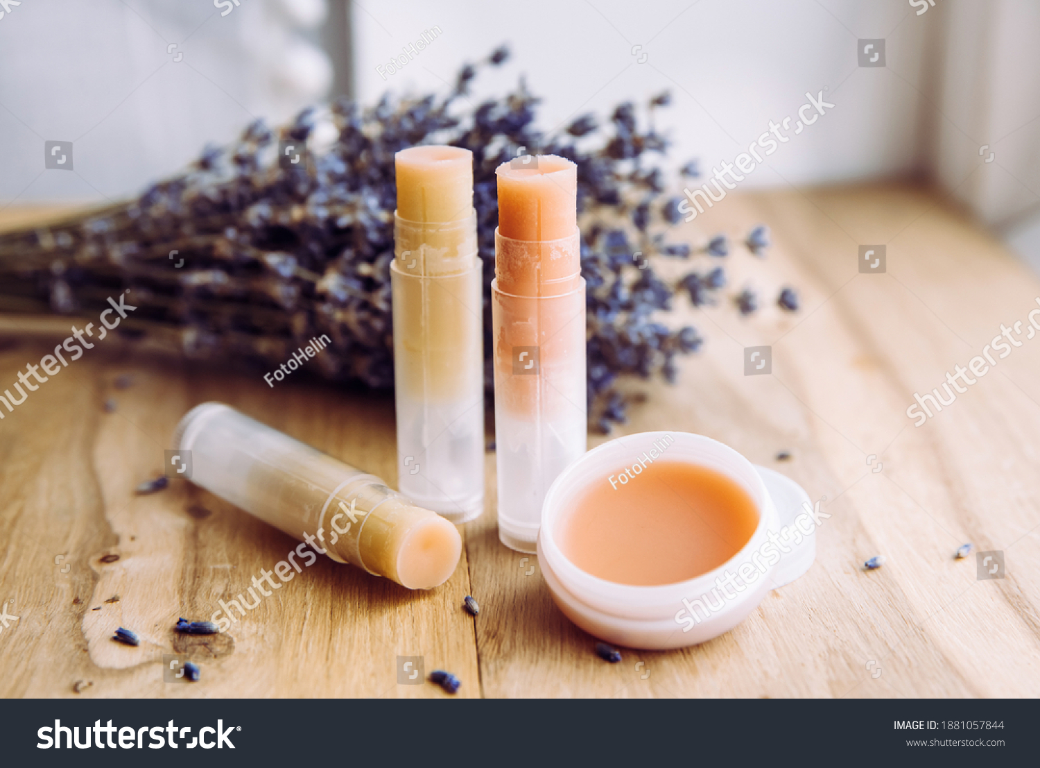Make homemade natural organic ingredients lip balm. Handmade lip balm and lipstick inside container on natural wooden background and lavender for decoration. #1881057844