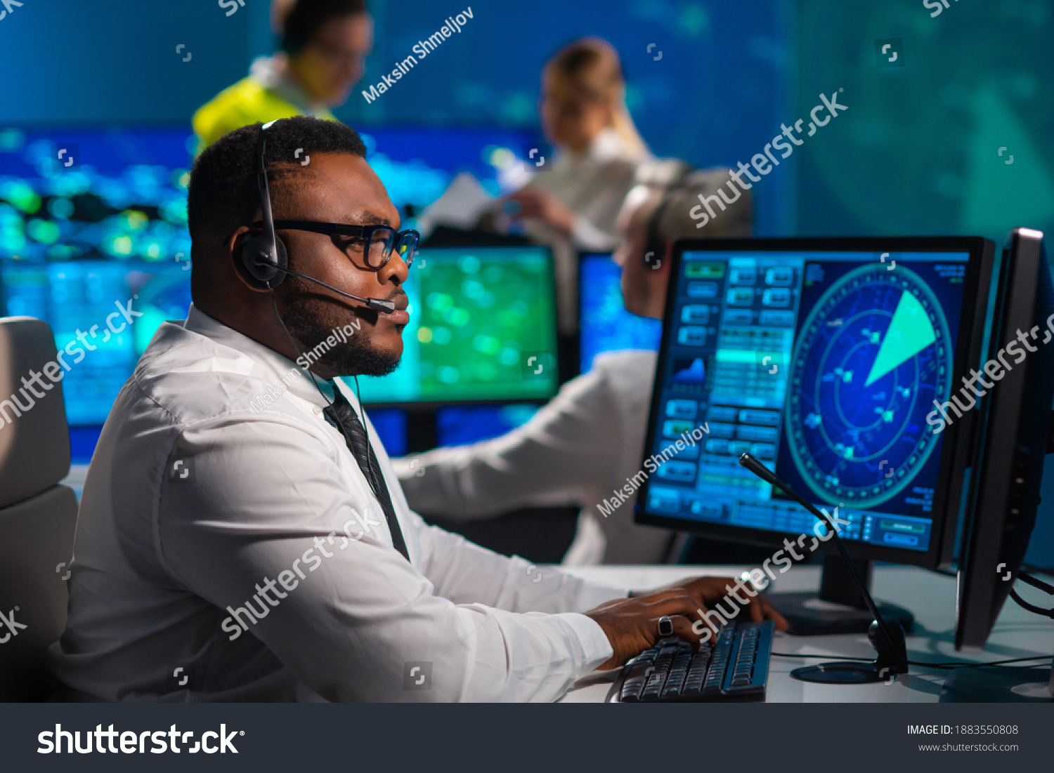 Workplace of the air traffic controllers in the control tower. Diverse team of aircraft control officers works using radar, computer navigation and digital maps. Aviation concept. #1883550808