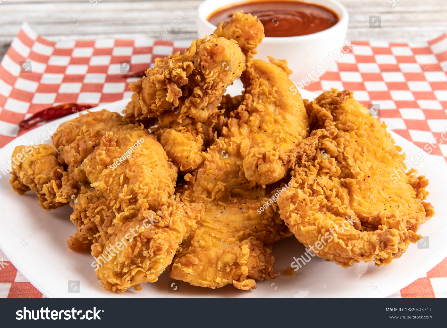 deep fried southern style breaded chicken tenders or chicken fingers on a white plate with dipping sauce #1885543711
