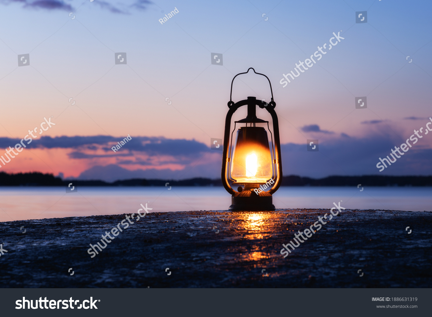 An old vintage oil lantern on a rock by the sea. Beautiful sunset sky and sea on background. Chill out travel concept. #1886631319