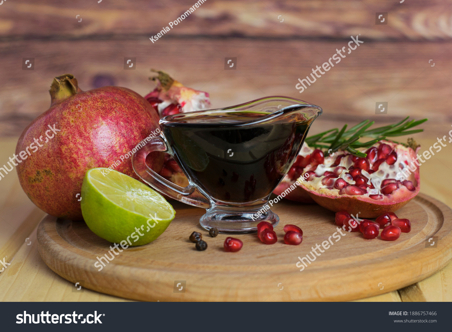 Pomegranate sauce in a gravy boat on a wooden board. Nearby are pomegranate, lime, pomegranate seeds. Narsharab, meat sauce, pomegranate sauce. #1886757466