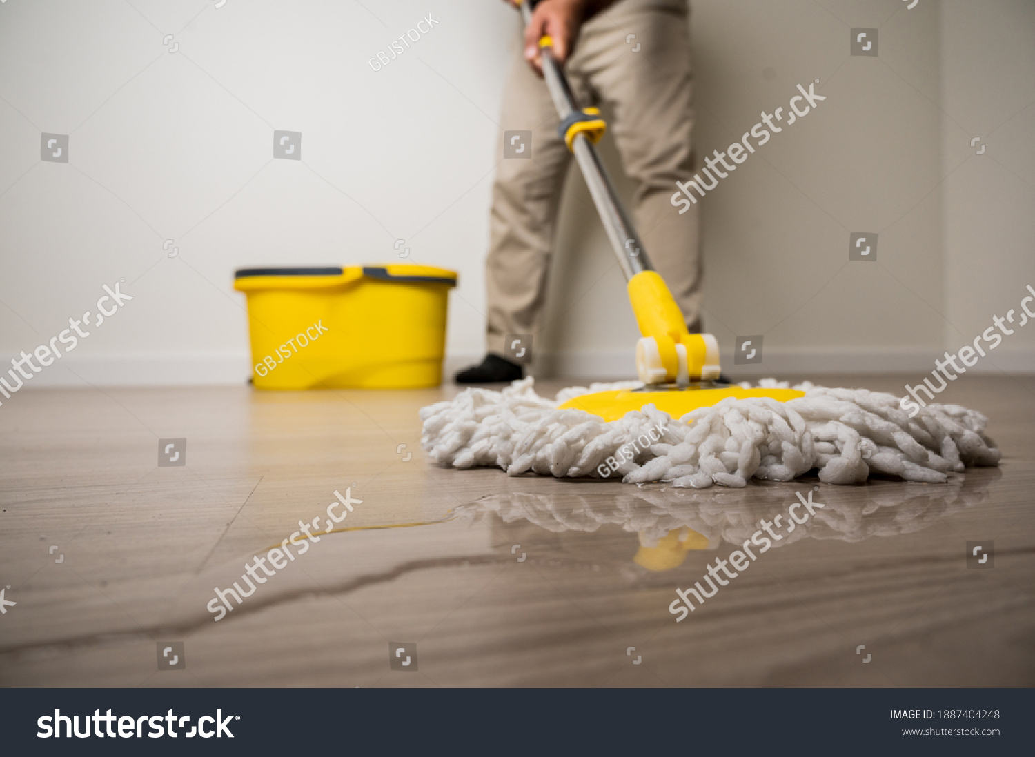 Cleaning workers mopping the wet area. There was spill water on the wooden floor in the living room. #1887404248