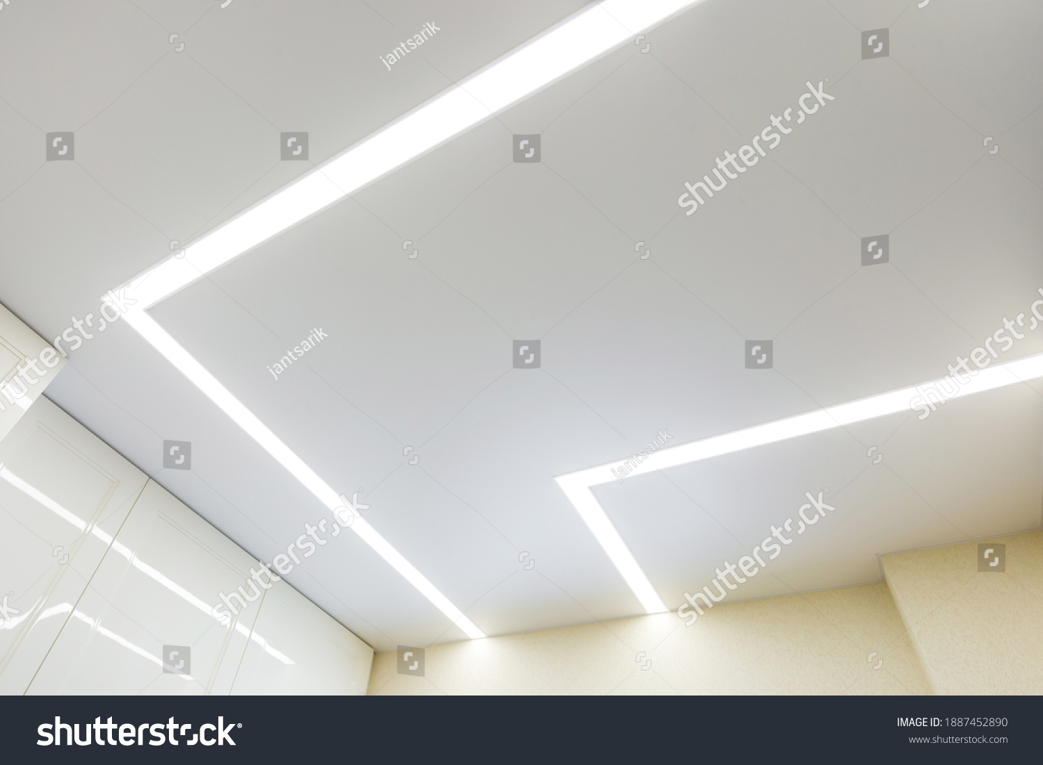 suspended ceiling with halogen spots lamps and drywall construction in empty room in apartment or house. Stretch ceiling white and complex shape. #1887452890