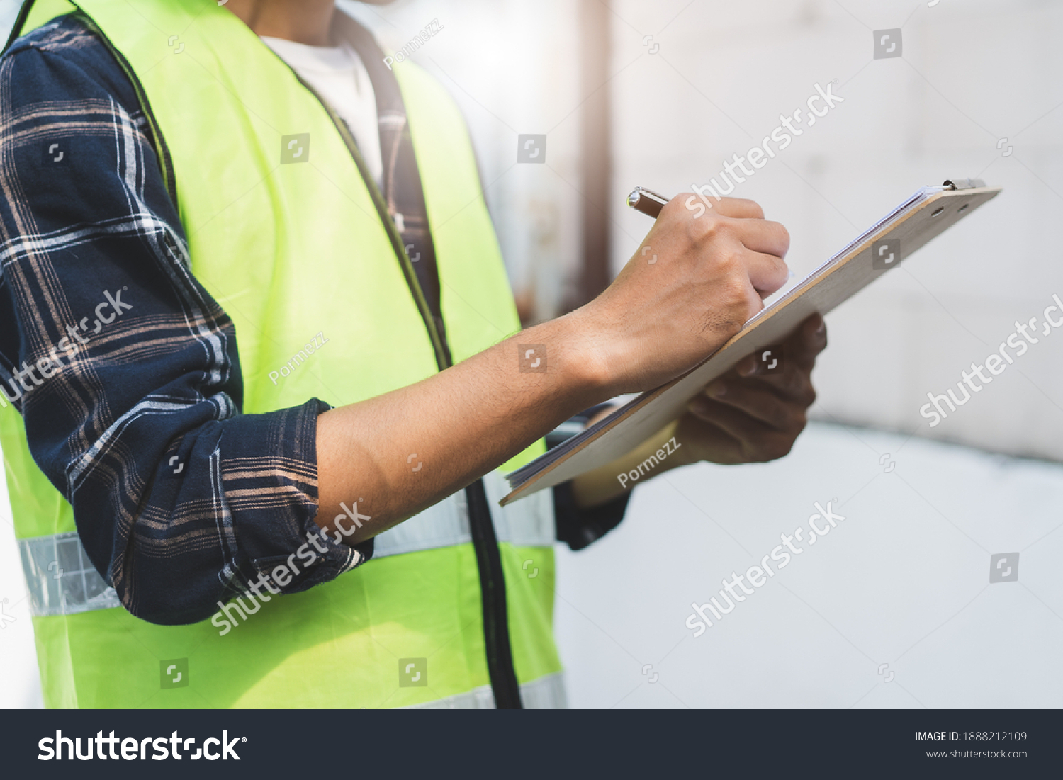 close up hands of inspector waer safety vest and checking list into clipboard #1888212109
