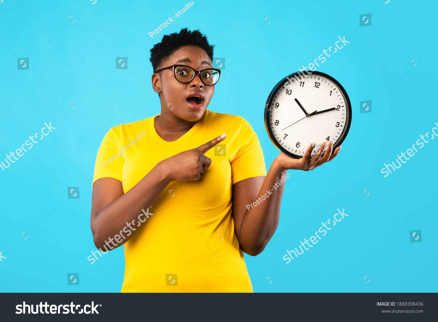 Deadline, Time Is Over. Oversized African Woman Showing Clock Posing Standing Over Blue Studio Background, Looking At Camera. Shocked Black Lady Being Late. Time's Tickling Concept #1888308436
