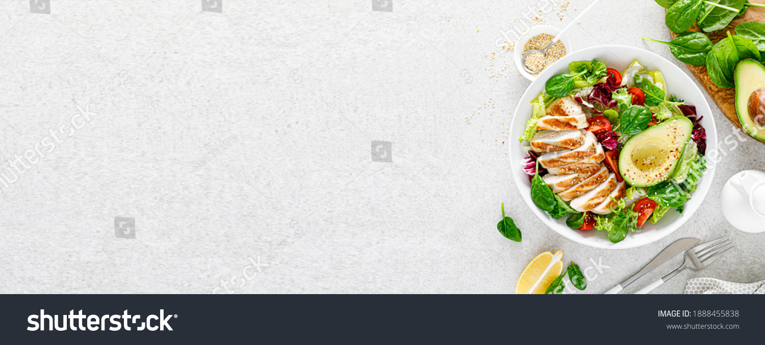 Grilled chicken meat and fresh vegetable salad of tomato, avocado, lettuce and spinach. Healthy and detox food concept. Ketogenic diet. Buddha bowl dish on white background, top view. Banner. #1888455838