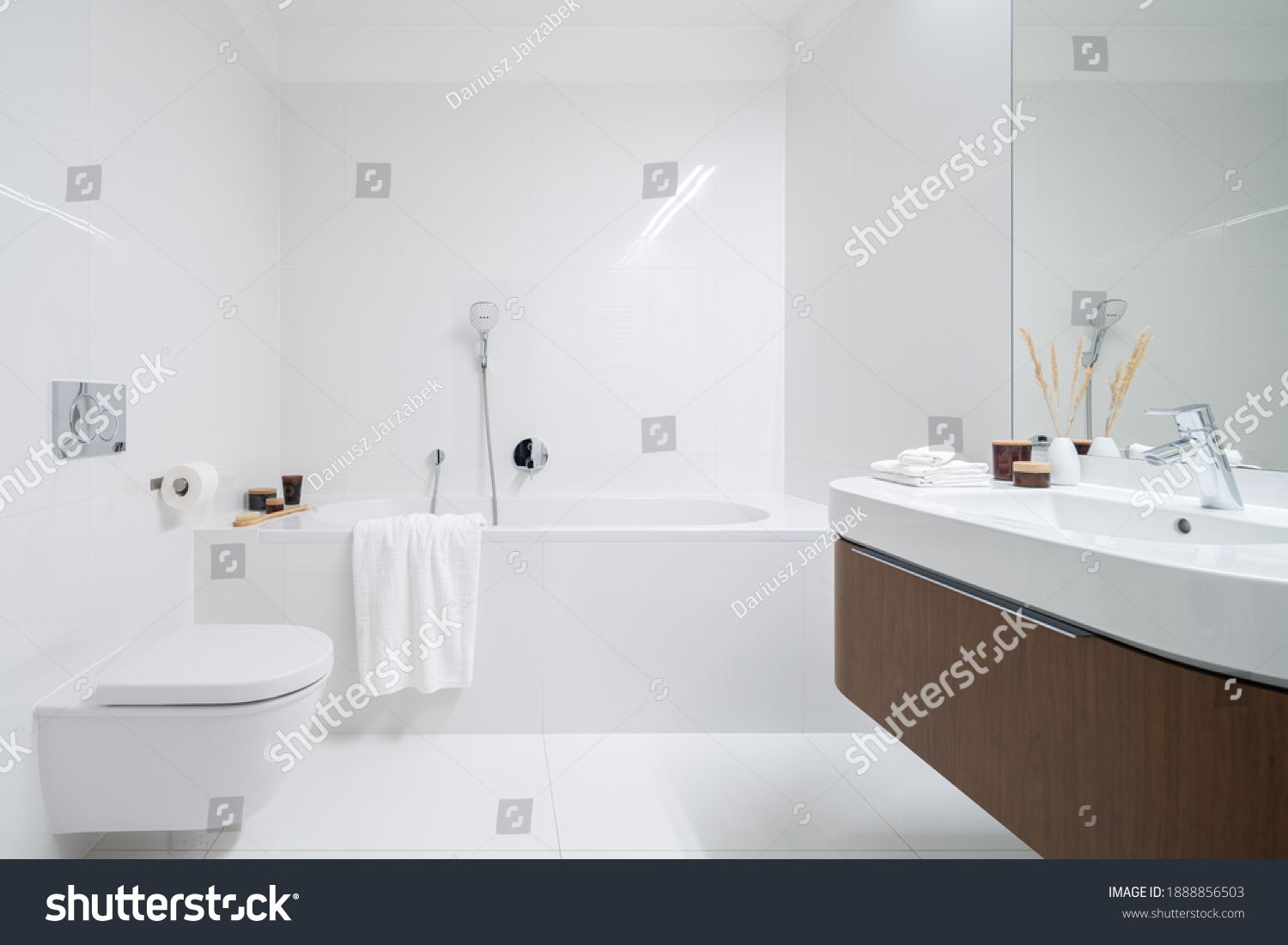 Spacious and elegant bathroom with big bathtub, white tiles, washbasin with wooden cabinet with drawer and big mirror #1888856503