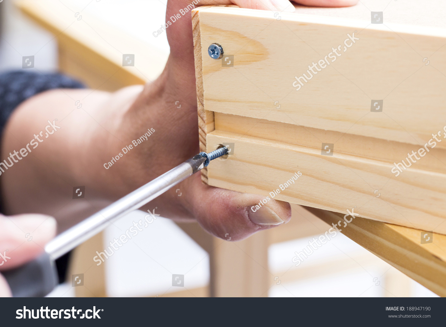 A carpenter builds a small white table with a screwdriver #188947190