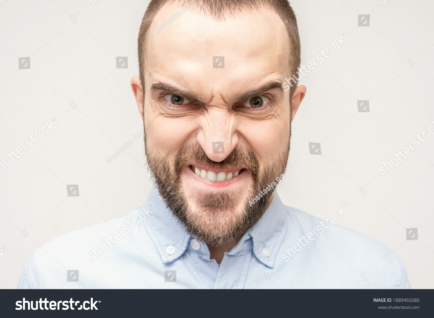 Gloating bearded man, portrait of an angry man with a grimace on his face, white background, close-up #1889492680